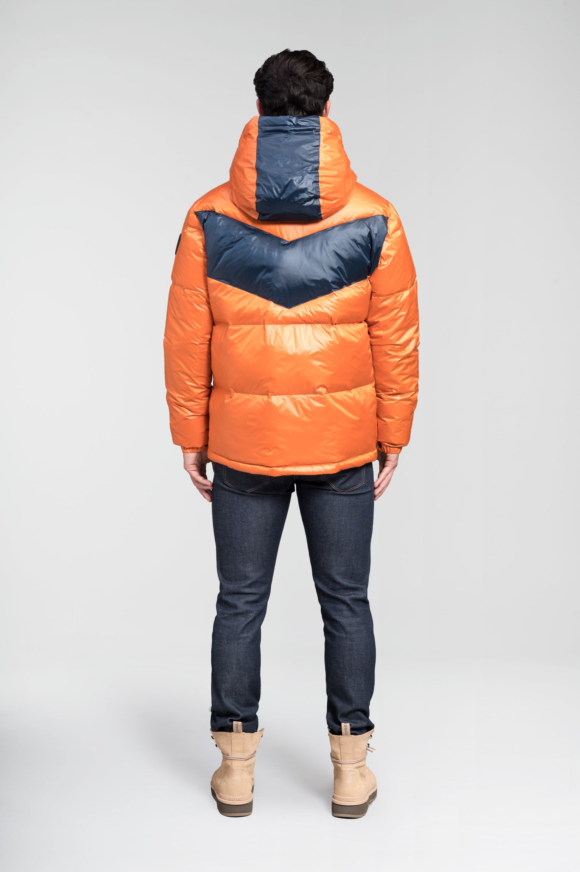 Dyna Men's Chevron Quilted Puffer Jacket in hip length, premium cire technical nylon taffeta fabrication, Premium Canadian origin White Duck Down insulation, non-removable down-filled hood, two-way centre-front zipper, fleece-lined zipper pockets at waist, pit zipper vents, in Burnt Orange