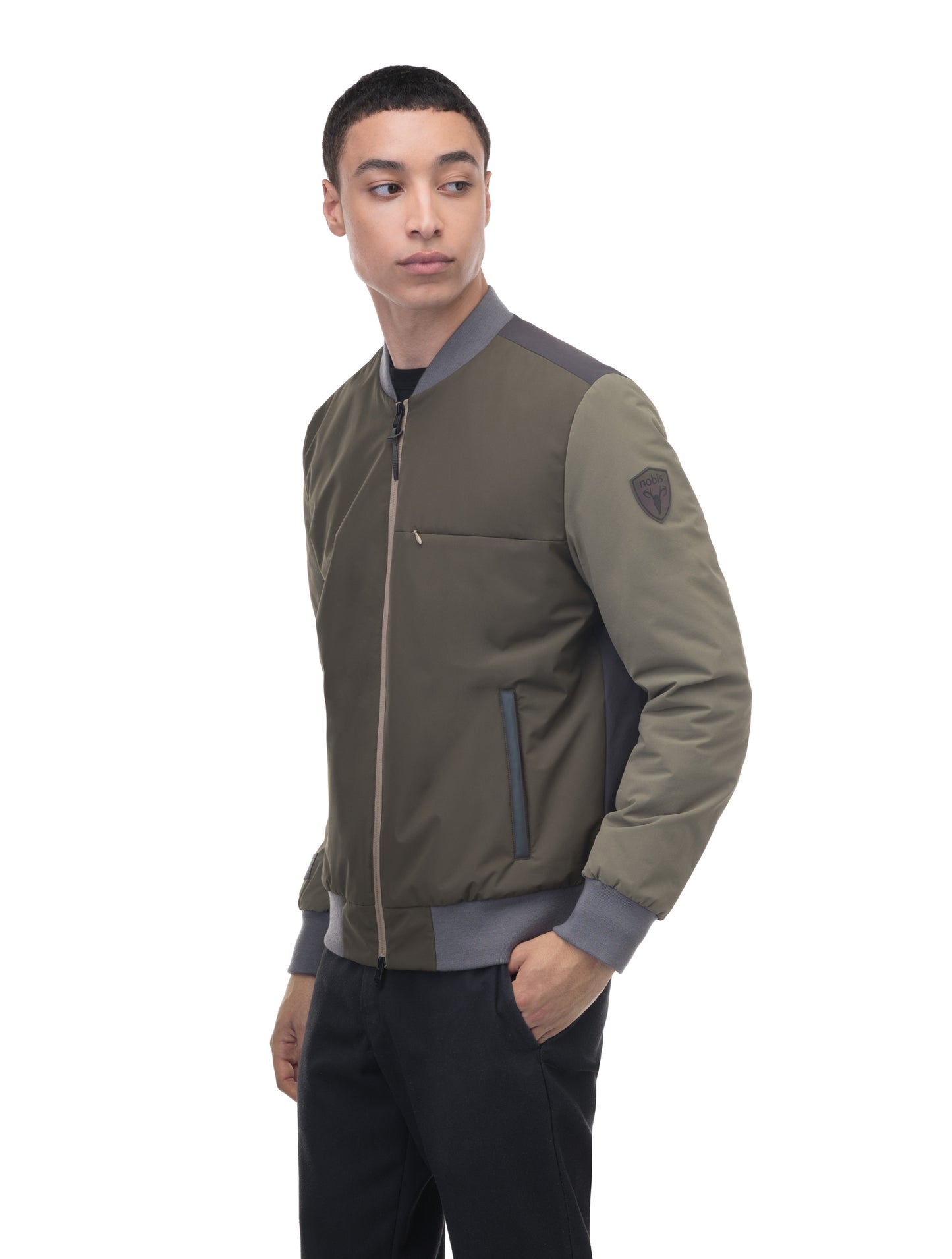 Unisex hip length bomber jacket with a contrast colour back panel, and zipper pockets at waist and an invisible zipper pocket at chest, in Dusty Olive/Licorice