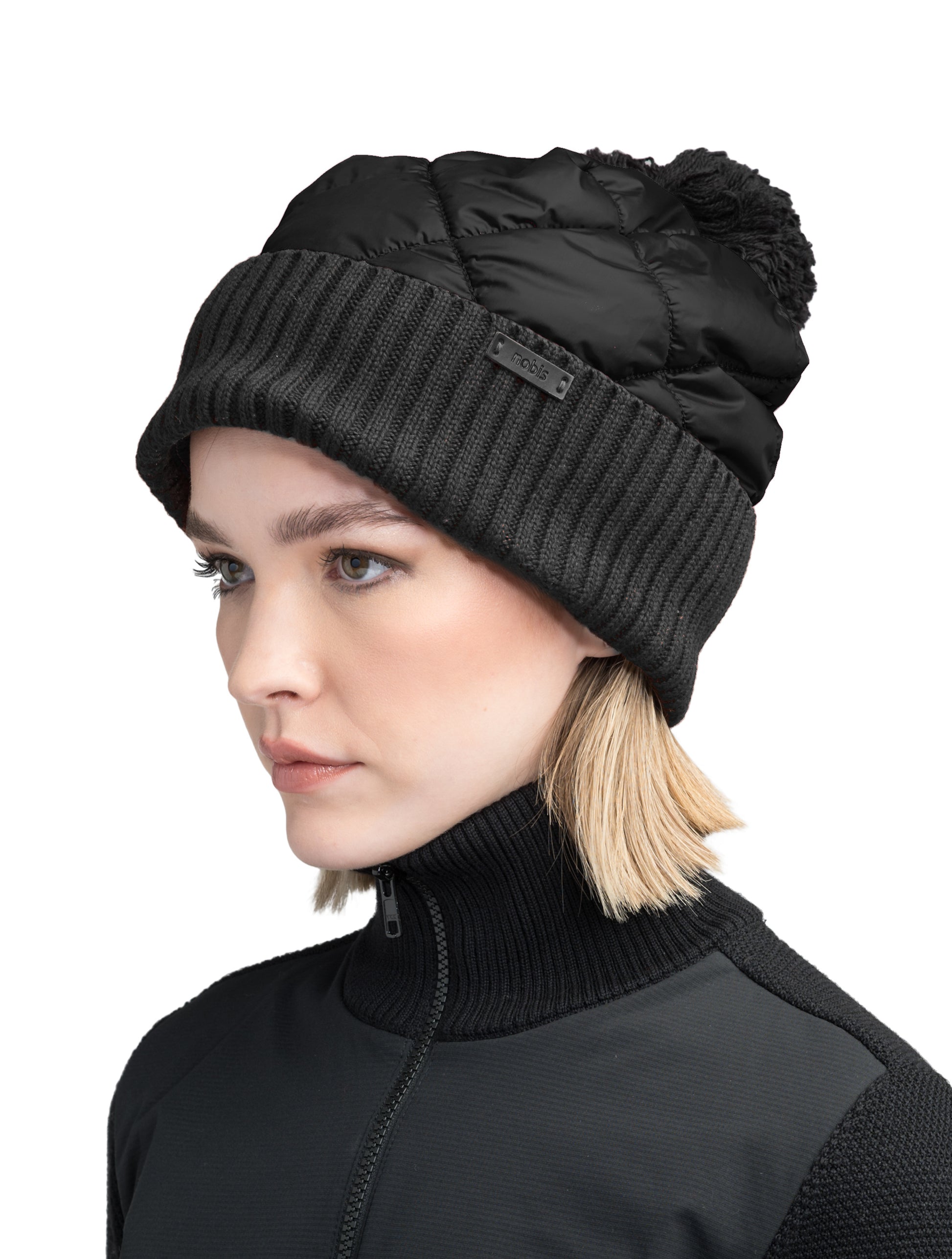 Lany Unisex Hybrid Pom Beanie in an extra fine merino wool blend and premium cire technical taffeta fabrication, rib knit cuff with leather Nobis wordmark detailing, quilted body, and plush pom-pom finish, in Black