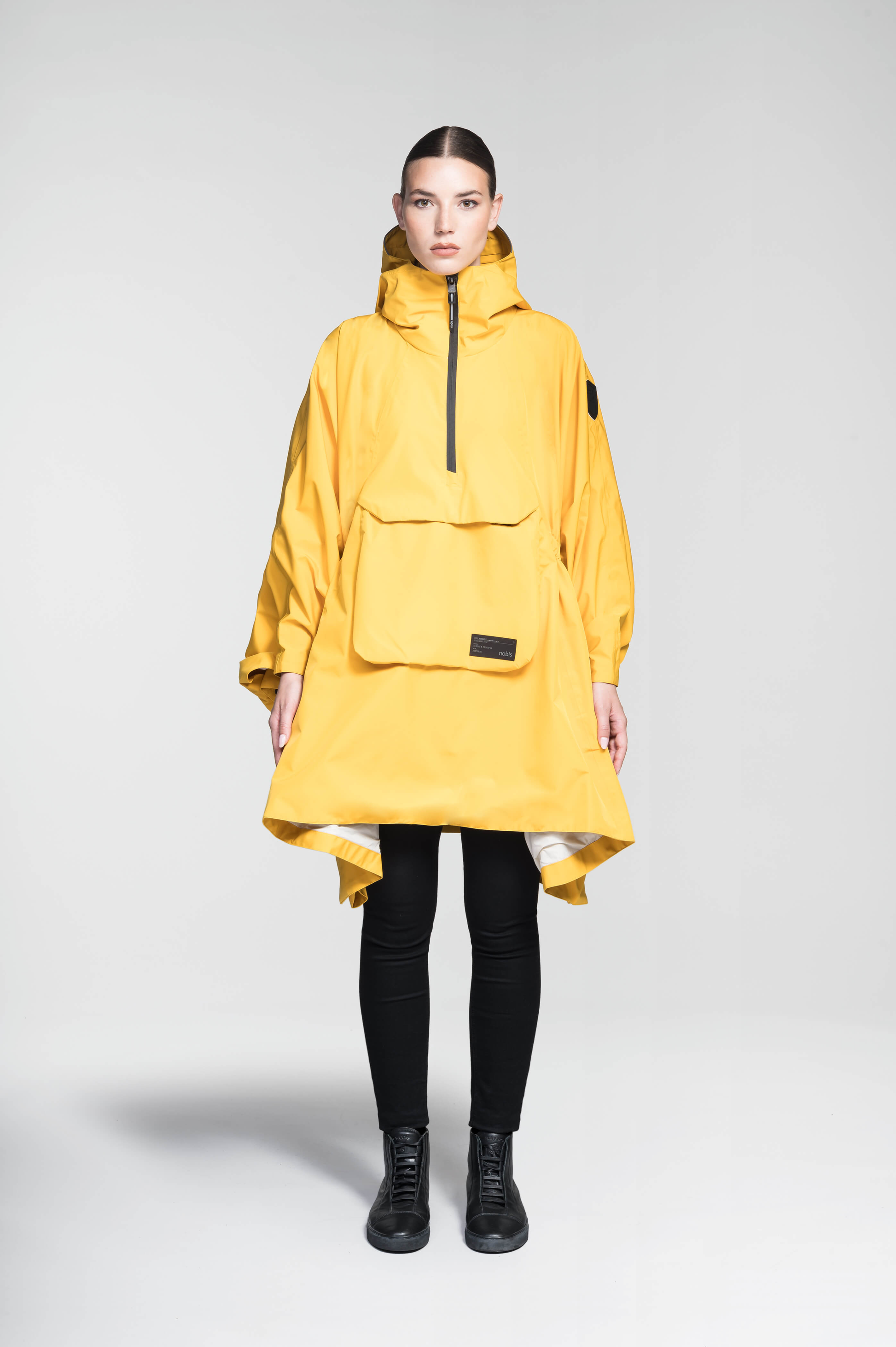 Hydra Unisex Performance Poncho in thigh length, non-removable hood, vertical half-zipper along centre front collar, hidden side-entry waist zipper pockets, adjustable webbing straps and snap closure cuffs, and packable to front kangaroo pocket with flap opening, in Old Gold