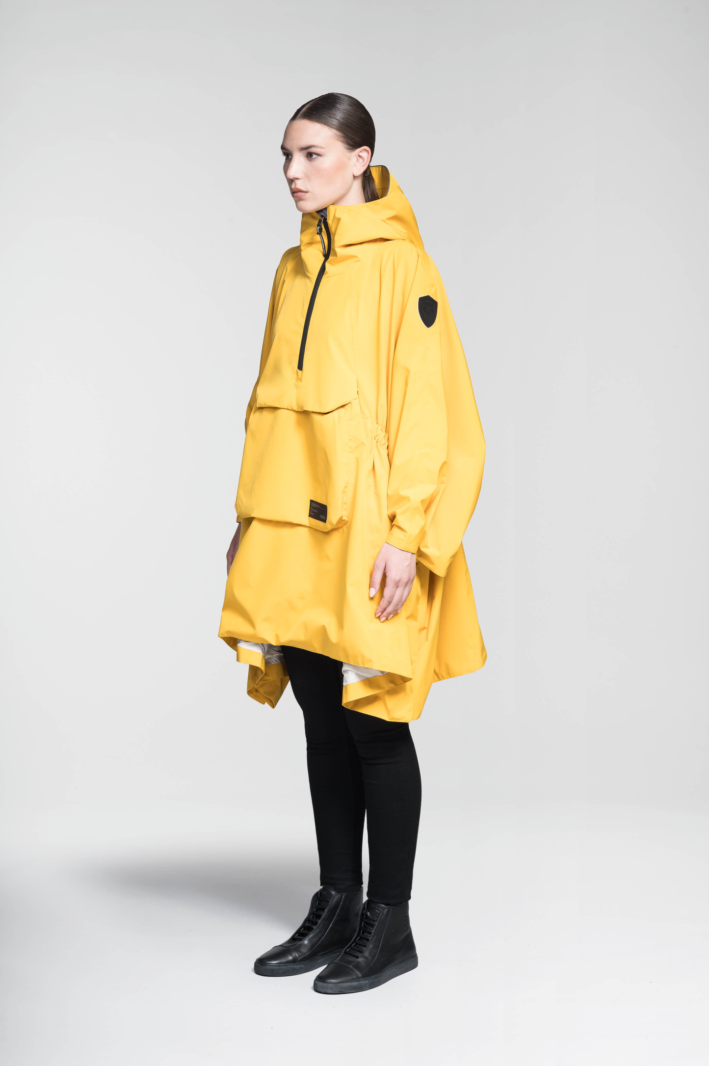 Hydra Unisex Performance Poncho in thigh length, non-removable hood, vertical half-zipper along centre front collar, hidden side-entry waist zipper pockets, adjustable webbing straps and snap closure cuffs, and packable to front kangaroo pocket with flap opening, in Old Gold