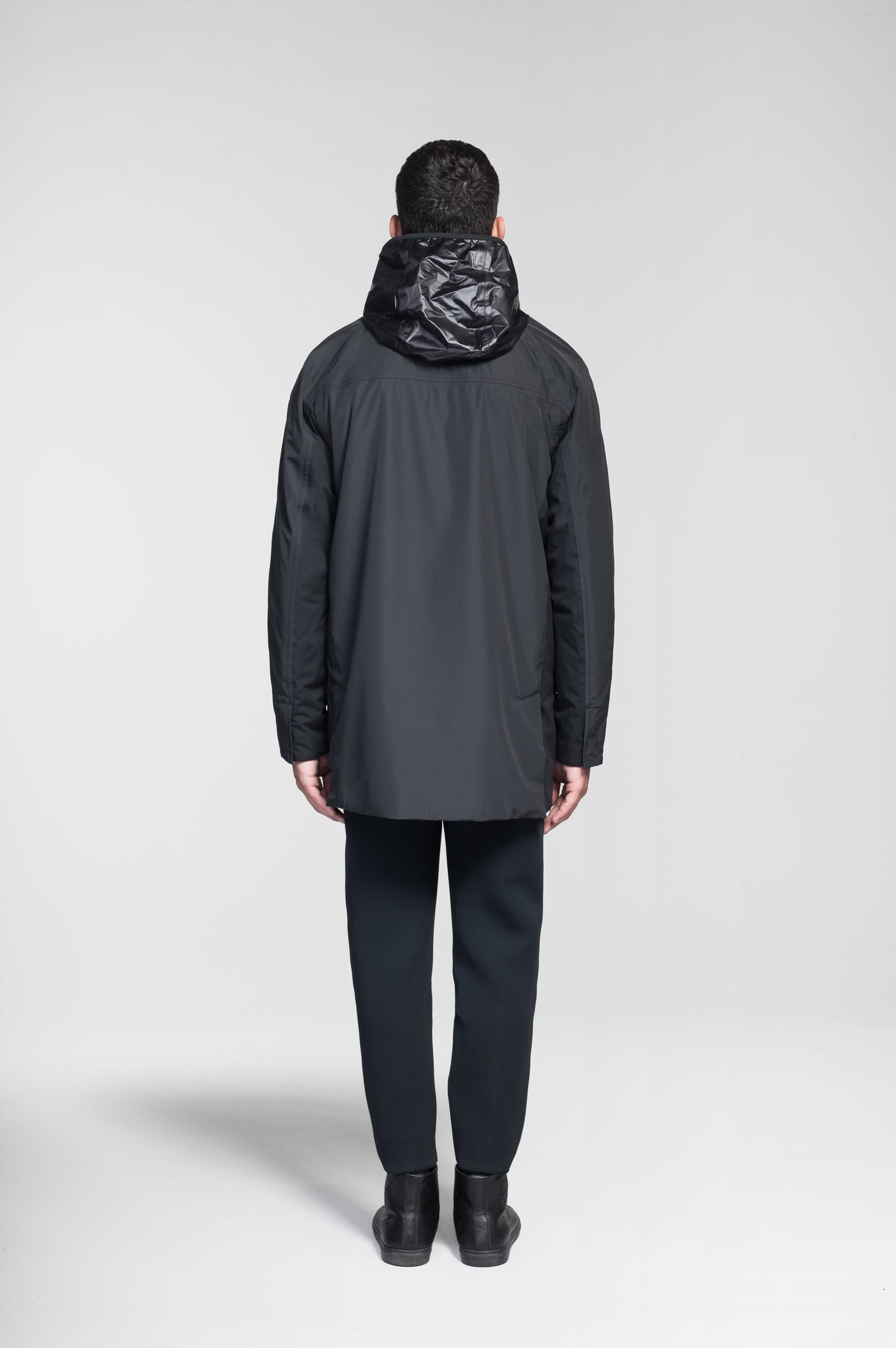 Pike Men's Tailored Mac Coat in thigh length, premium 3-ply Micro Denier fabrication at body and cire technical nylon taffeta fabrication at hood, premium 4-way stretch, water resistant Primaloft Gold Insulation Active+, hidden 2-way zipper with snap closure wind flap, single welt pockets with magnetic closure at waist, hidden snap placket at cuffs, pit zippers for ventilation, interior zipper pocket at right chest, and interior button pocket at left chest, in Black