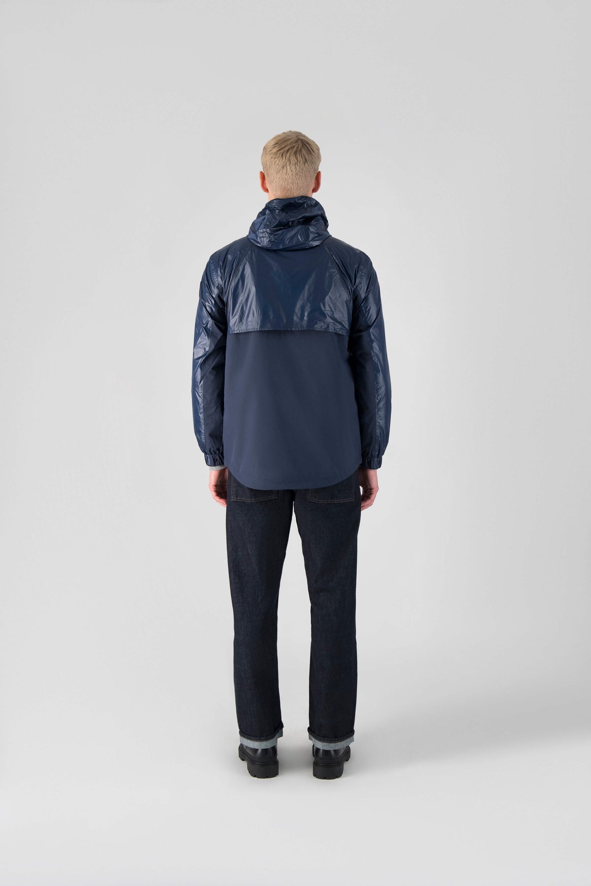 Stratus Men's Tailored Packable Rain Jacket in hip length, premium cire technical nylon taffeta and stretch ripstop fabrication, highly breathable mesh lining, hidden packable pocket, non-removable hood with adjustable draw cord, reflective piping along front and back, underarm grommets for extra breathability, back yoke with mesh ventilation, two waist zipper pockets, two interior zipper pockets, elastic cuffs with adjustable snap button, and adjustable interior draw cord at waist hem, in Marine