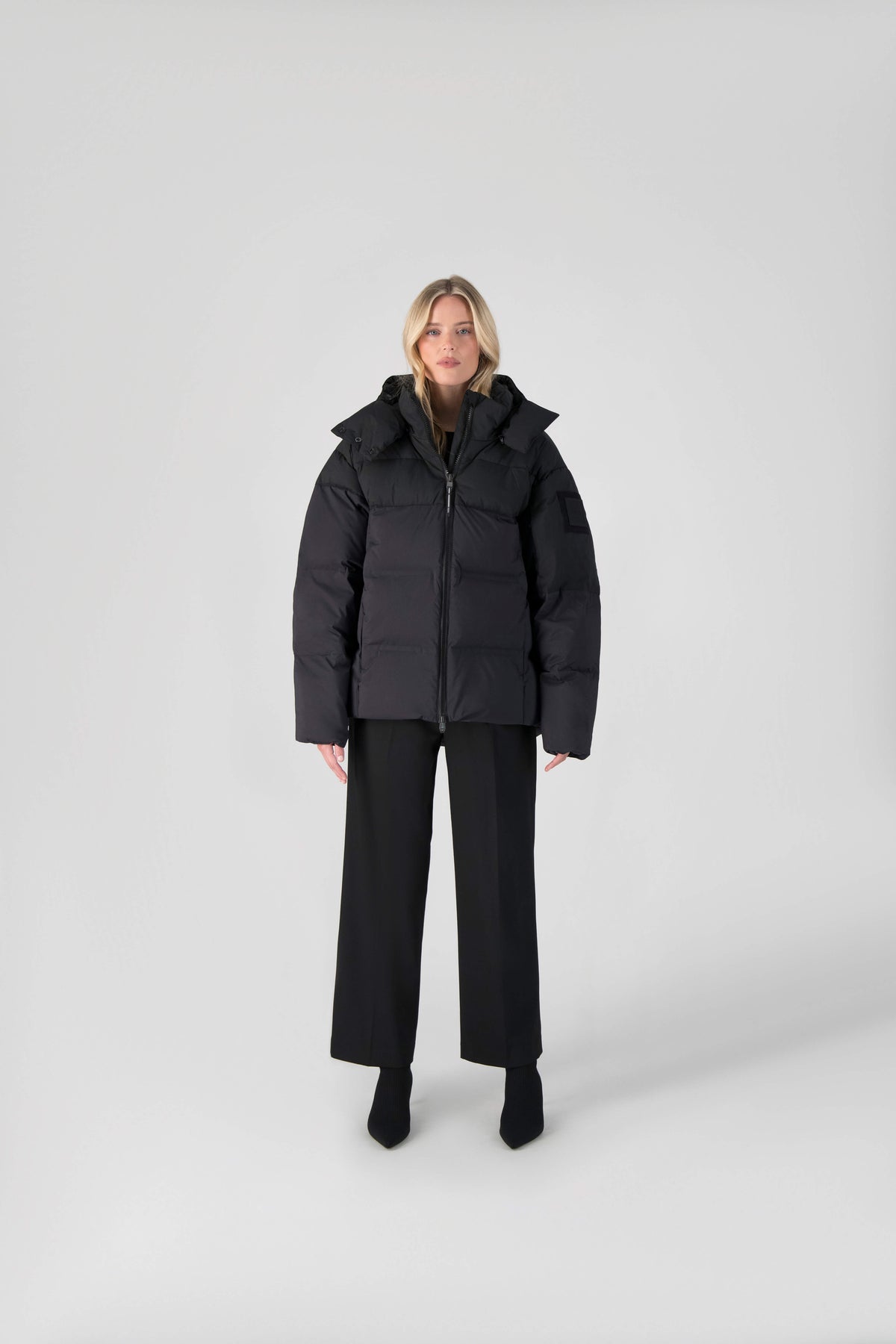 Una Ladies Performance Puffer in hip length, Technical Taffeta and Durable Stretch Ripstop fabrication, Premium Canadian White Duck Down insulation, removable down filled hood, centre front two-way zipper, and side-entry pockets at waist, in Black