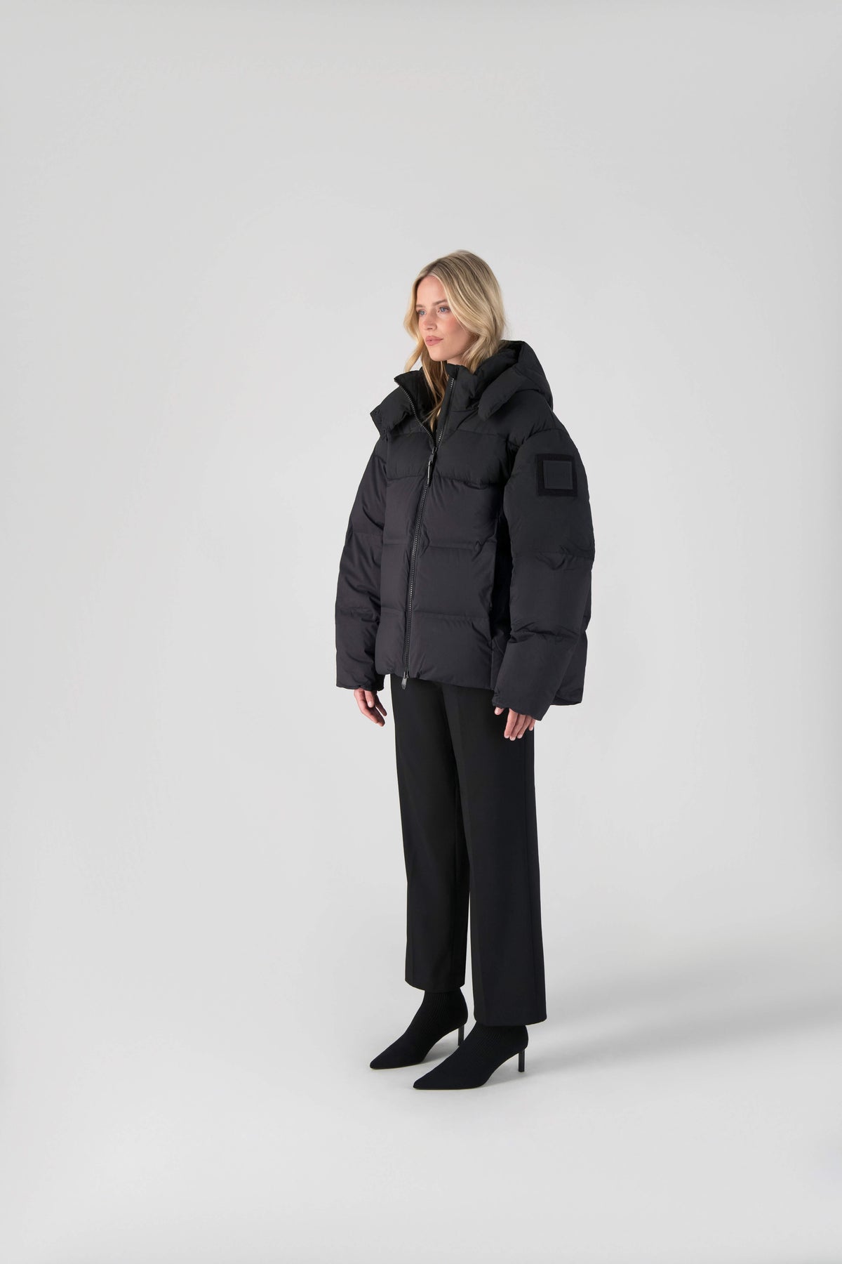 Una Ladies Performance Puffer in hip length, Technical Taffeta and Durable Stretch Ripstop fabrication, Premium Canadian White Duck Down insulation, removable down filled hood, centre front two-way zipper, and side-entry pockets at waist, in Black